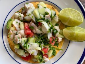 shrimp ceviche tostada on a plate with two sliced limes