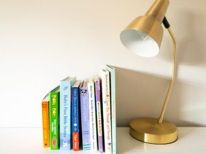 9 best baby books on a shelf and a gold lamp