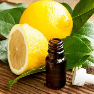 fresh lemons and open bottle of essential oil