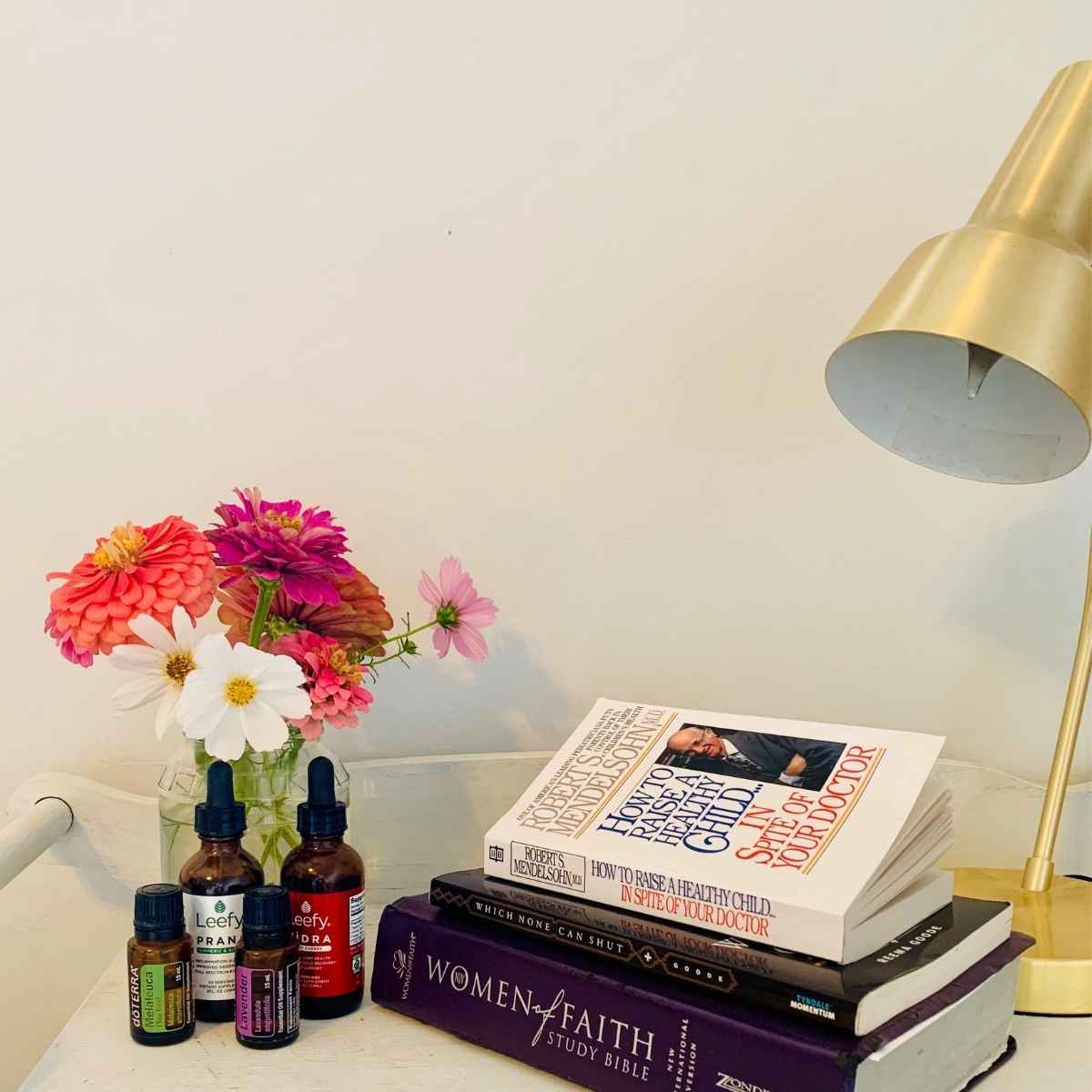 nightstand with fresh flowers essential oils and books for stay at home moms.
