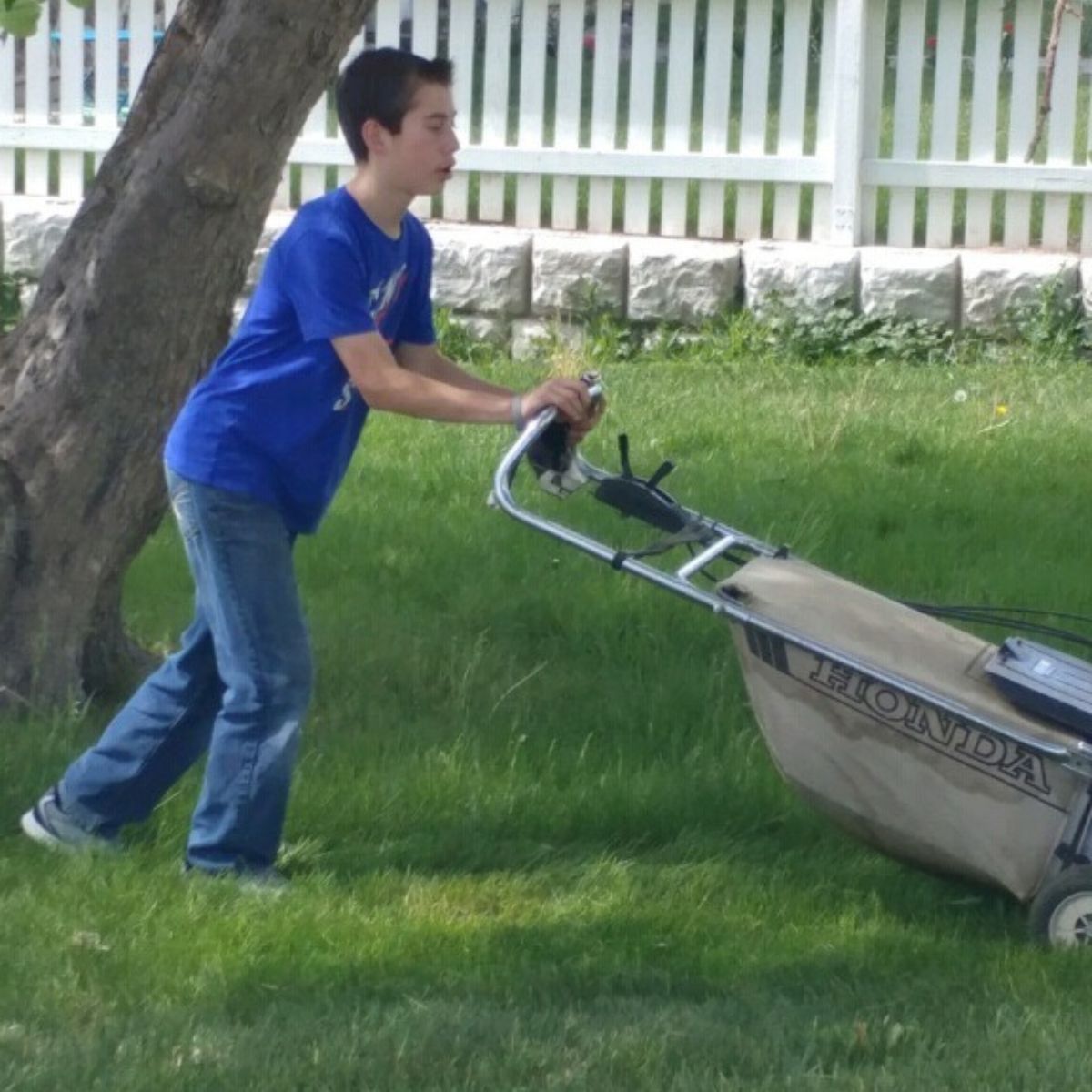 boy mowing the lawn to earn some spending money
