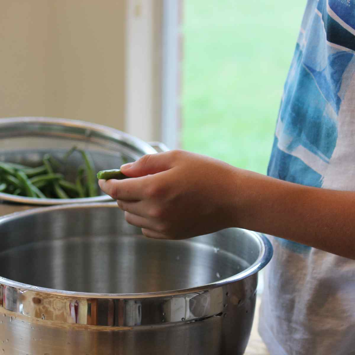 boy helping to clean green beans for dinner