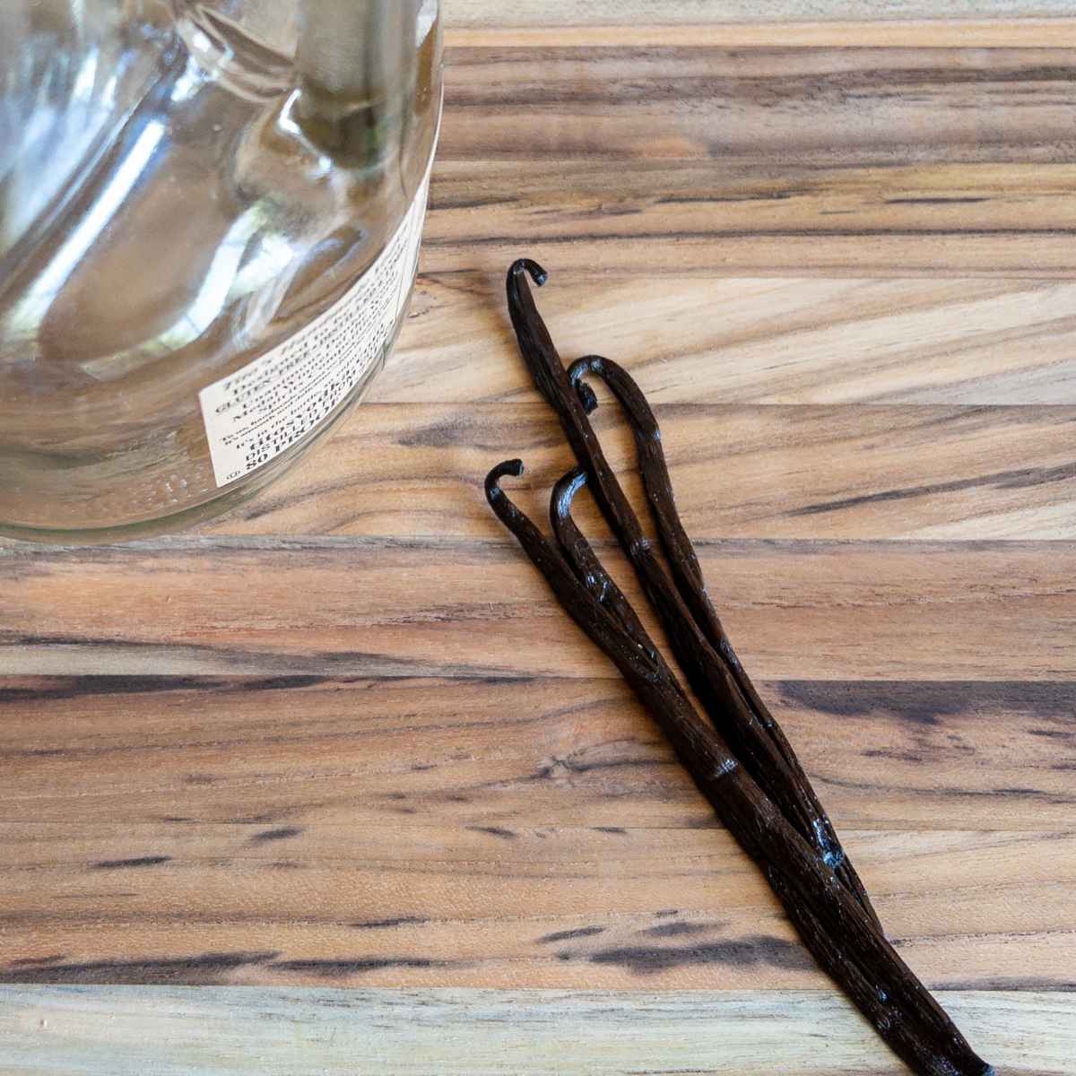 madagascar vanilla beans on a cutting board next to an empty bottle of vodka